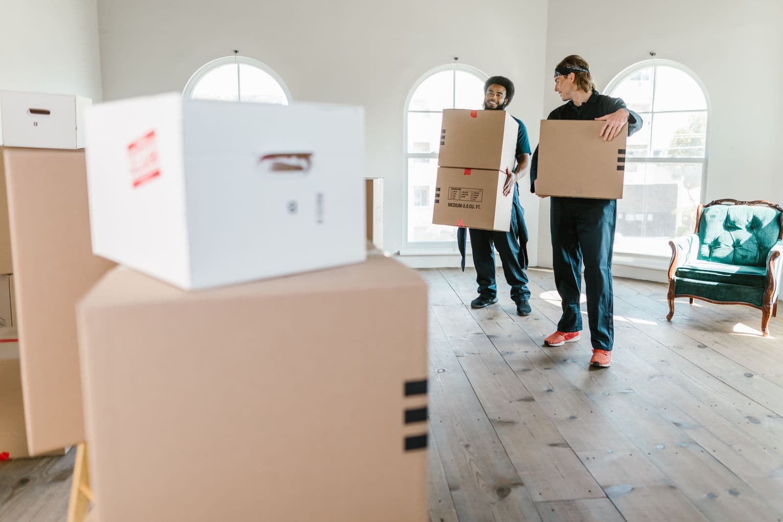 Movers carrying boxes out to a truck outside a home